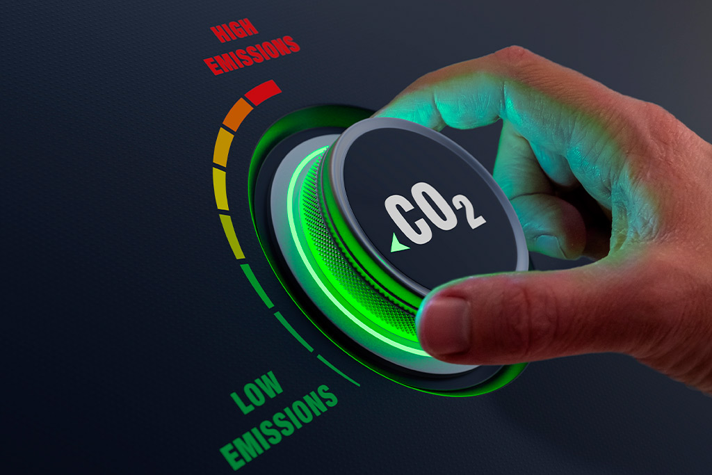 A hand activating a 'CO2 Low Emissions' button on a dark backdrop, representing sustainable travel options like charter buses.