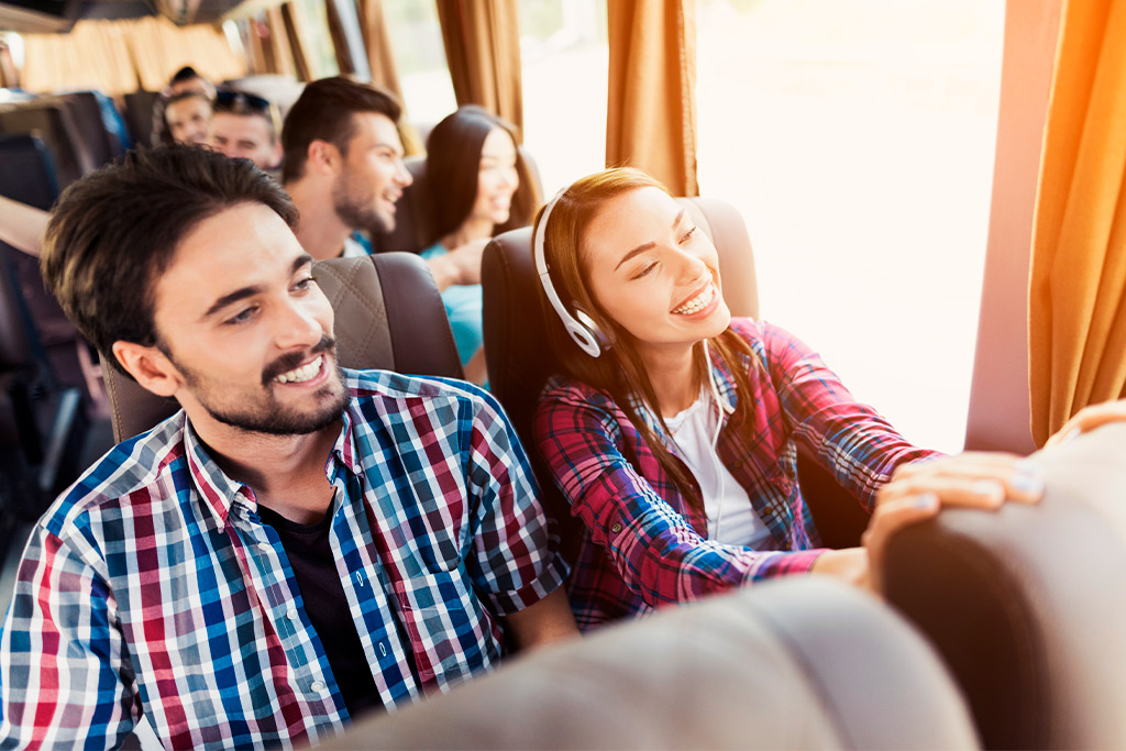 Passengers on a bus with headphones, illustrating the environmental advantages of using charter buses for travel.
