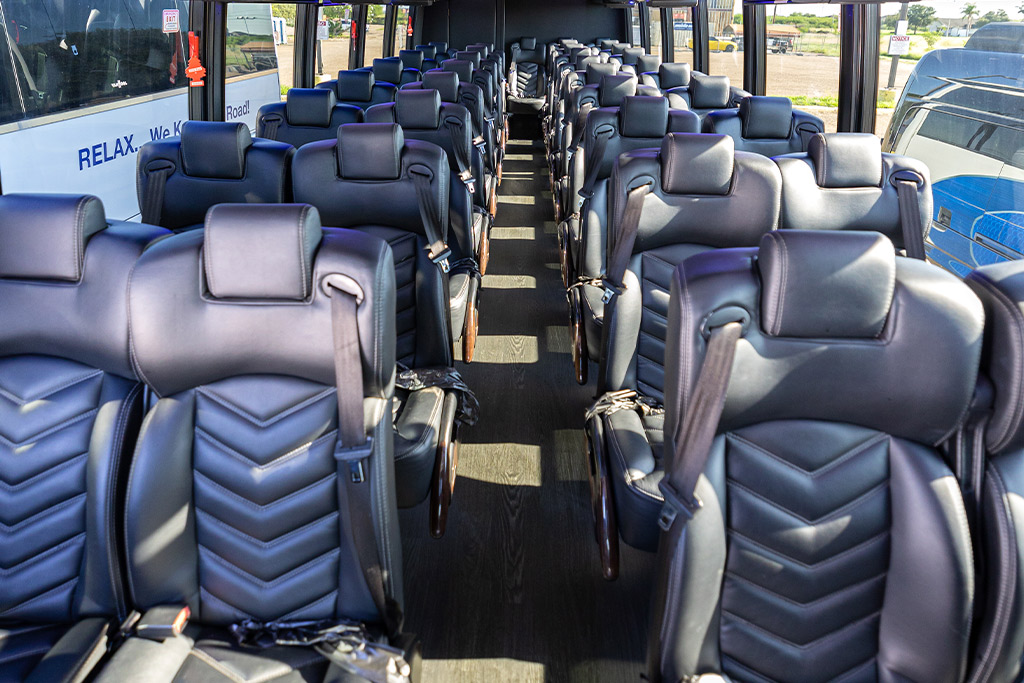 A spacious bus featuring numerous seats upholstered in black leather, ideal for group travel considerations.